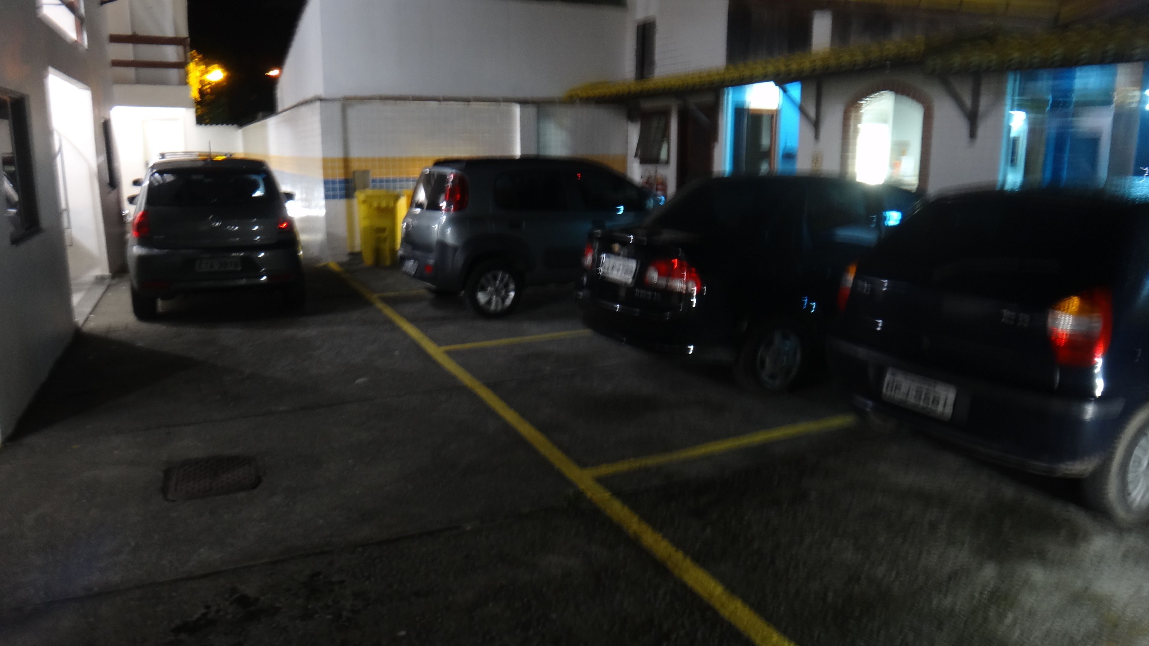 Um estacionamento com vários carros estacionados em vagas demarcadas.