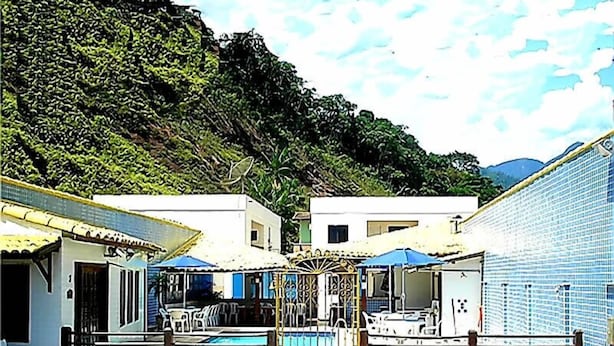 A courtyard with a pool, surrounded by buildings with tiled walls and a gate. - Pousada Praia da Ribeira Clube (Angra dos Reis)