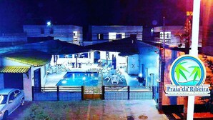 A hotel with a pool area, a dining space, and a sign indicating 'Praia da Ribeira'. - Pousada Praia da Ribeira Clube (Angra dos Reis)
