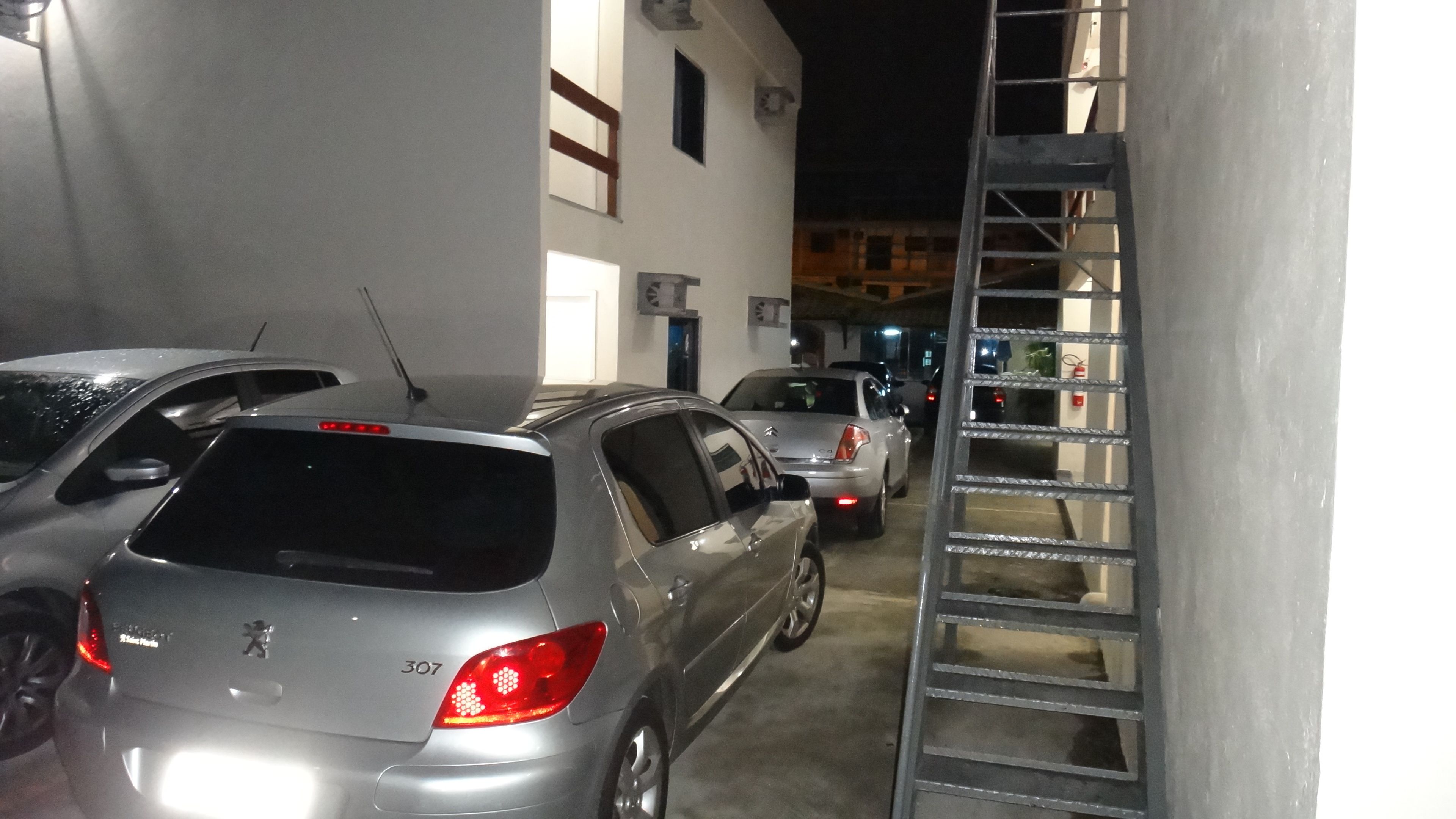 Un parking souterrain où sont garées plusieurs voitures, dont une berline argentée portant le numéro 307 à l’arrière.
