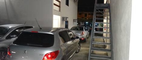 Un estacionamiento con varios coches aparcados, incluyendo un sedán plateado con el número 307 en la parte trasera.
