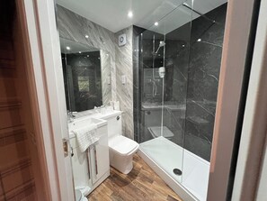 A modern bathroom with a glass-enclosed shower, a white sink, and a toilet. - King Robert Hotel (Stirling)