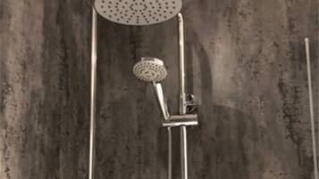 A shower with a handheld showerhead and a wall-mounted faucet.