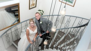 Una pareja en una escalera de caracol de diseño moderno, con un espejo y cuadros en las paredes.