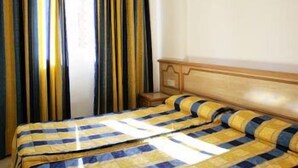 A hotel room with a bed, curtains, and a wooden headboard. - Benimar (Benidorm)