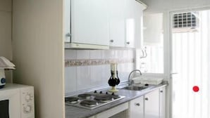 A kitchen with white cabinets, a microwave, a gas stove, and a window with a view. - Benimar (Benidorm)