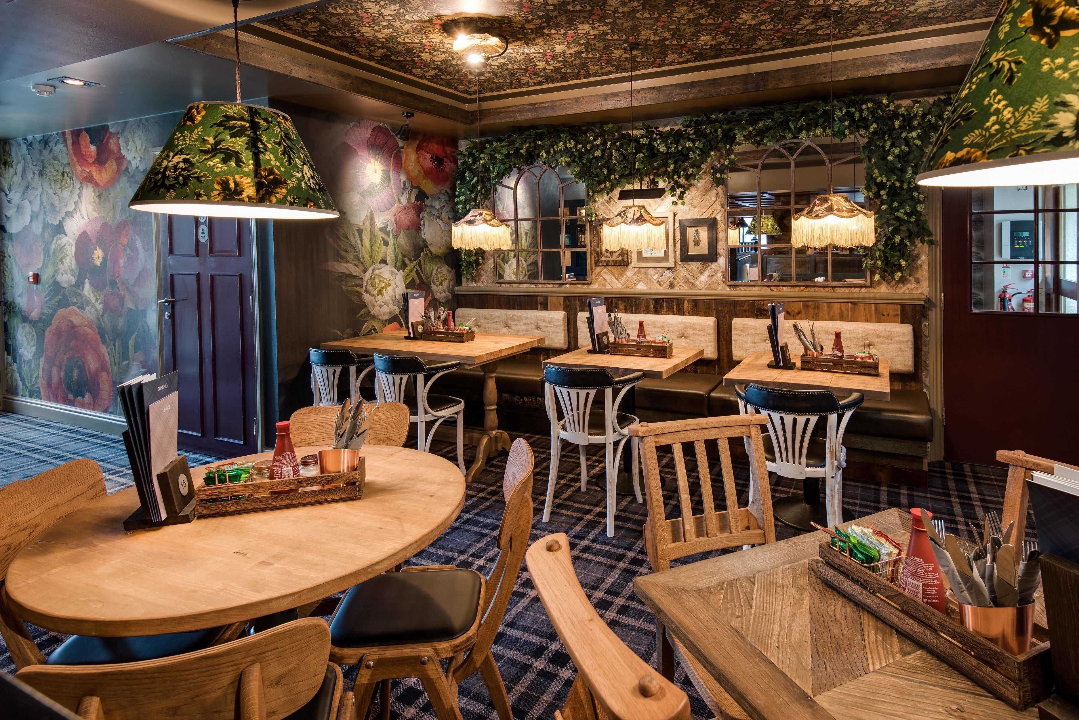 A restaurant with wooden tables and chairs, floral wall art, and hanging lamps.