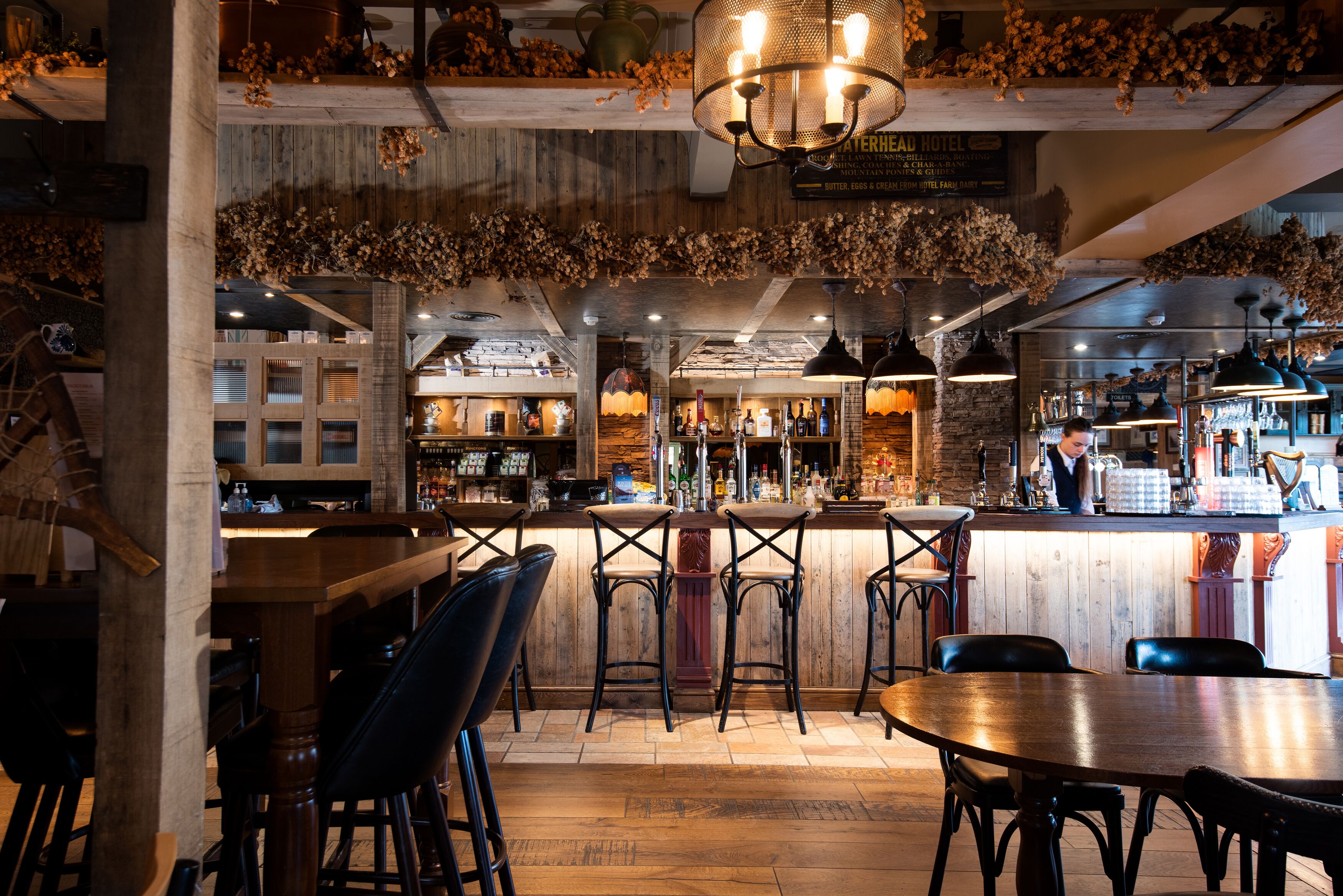 Un espace bar avec des meubles en bois, un comptoir et des décorations florales suspendues.