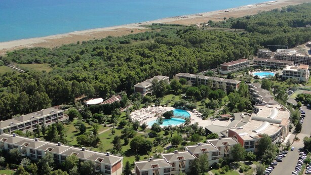 A resort with multiple buildings, a swimming pool, and a beach in the background. - Akiris (Nova Siri)