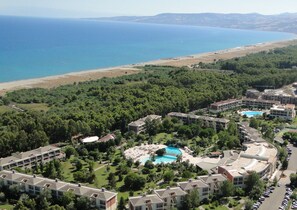 A resort with multiple buildings, a swimming pool, and a beach in the background. - Akiris (Nova Siri)
