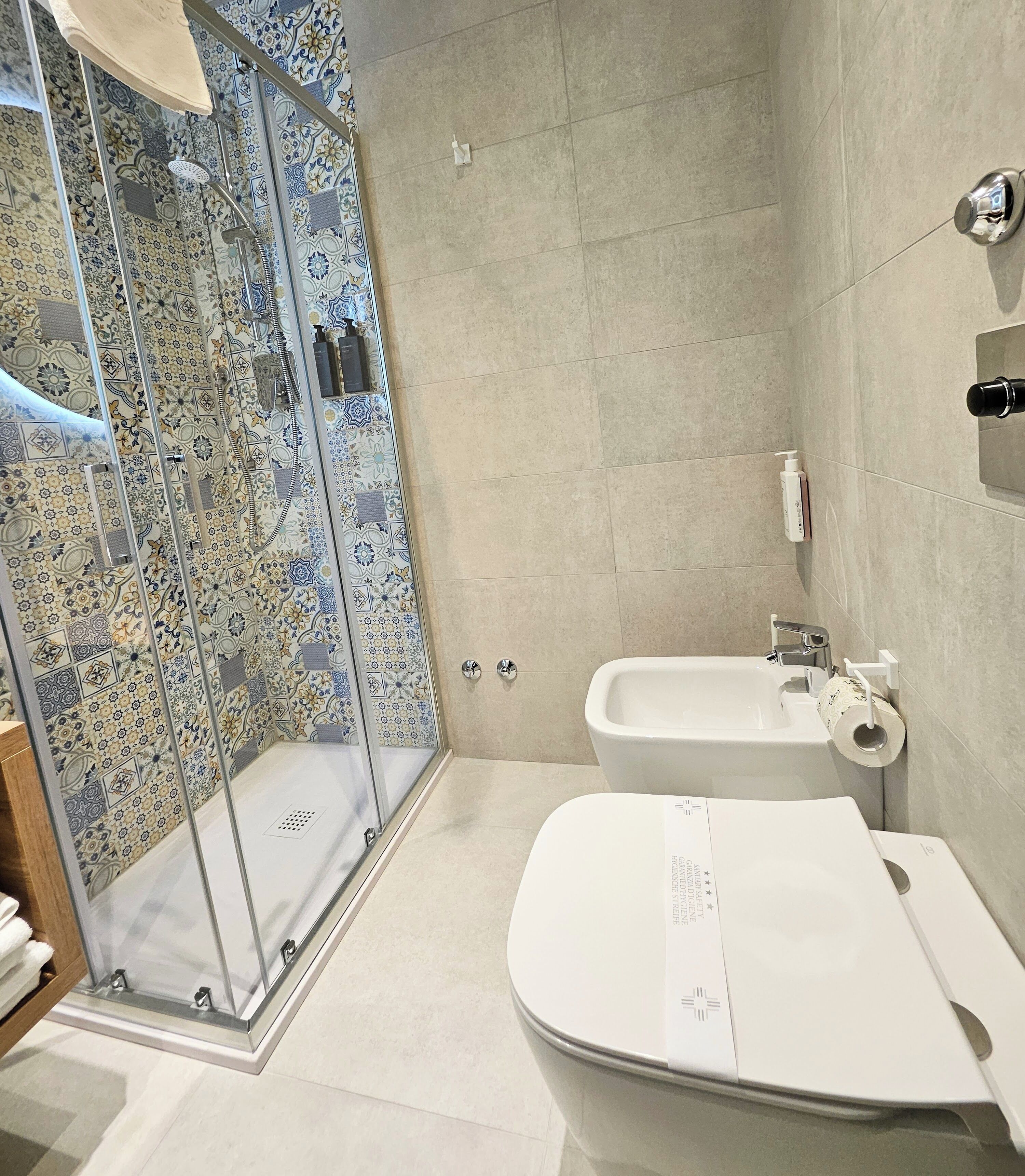 A modern bathroom with a glass-enclosed shower, a white sink, and a bidet.