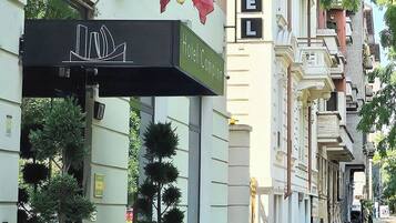 Um hotel com letreiros, bandeiras e plantas em vasos.