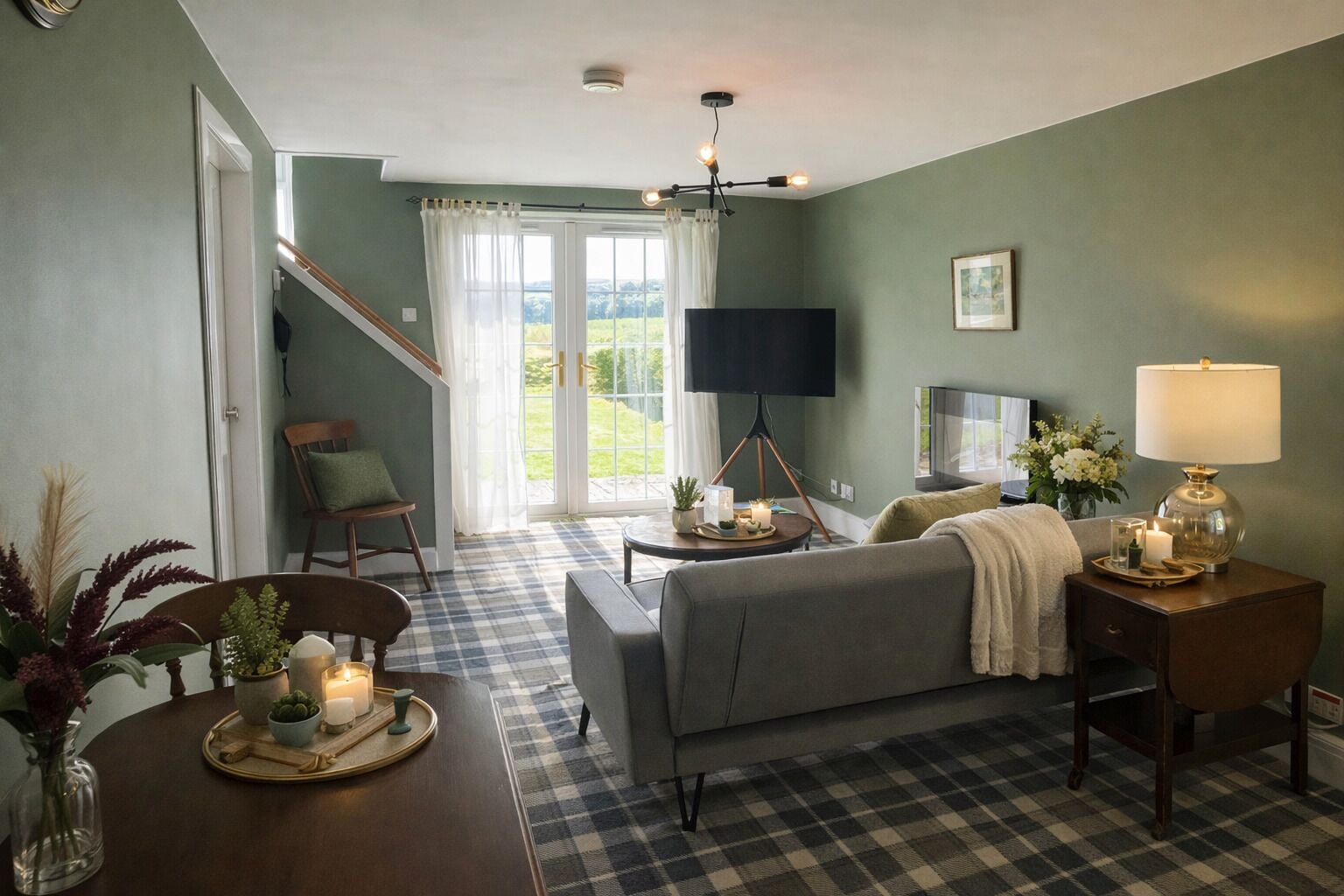 A cozy living room with a checkered floor, a sofa, a TV, and a dining table with a vase of flowers.