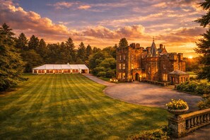 A large, historic building with a well-maintained lawn and a white tent structure nearby. - Friars Carse Country House Hotel (Dumfries)