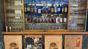 Eine Bar mit Regalen voller Spirituosenflaschen und Gläsern.