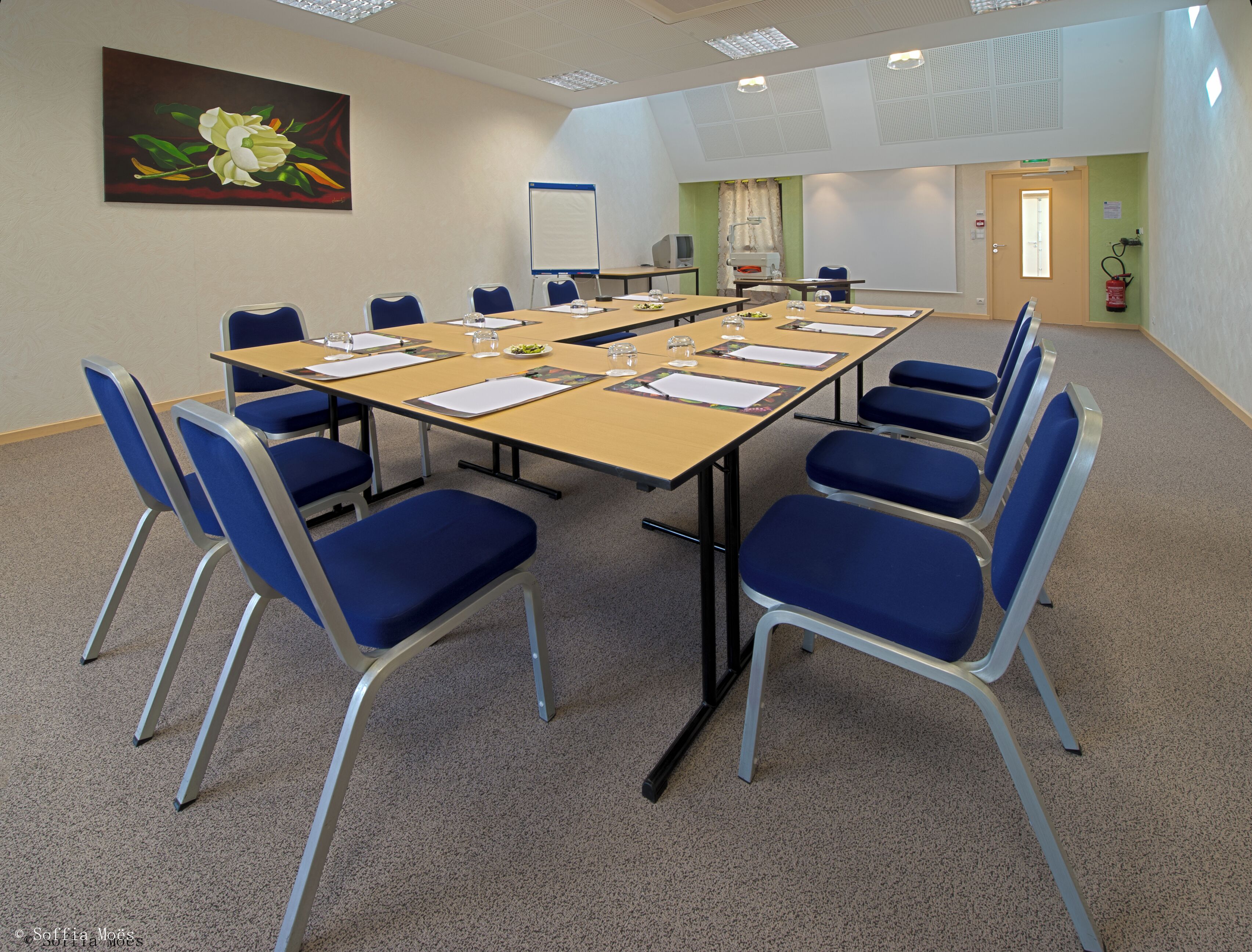 A conference room with a long table, blue chairs, and a whiteboard.