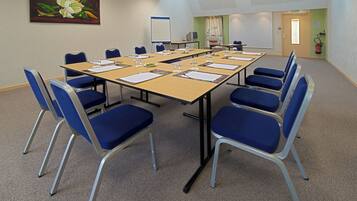 A conference room with a long table, blue chairs, and a whiteboard.