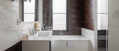 A modern bathroom with a large bathtub, a double sink vanity, and a large mirror.
