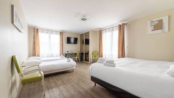 Habitación de hotel con dos camas, un escritorio, una silla y un televisor.