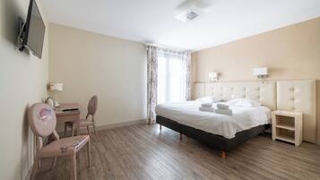 A hotel room with a bed, a desk, a chair, a TV, and a window with curtains.