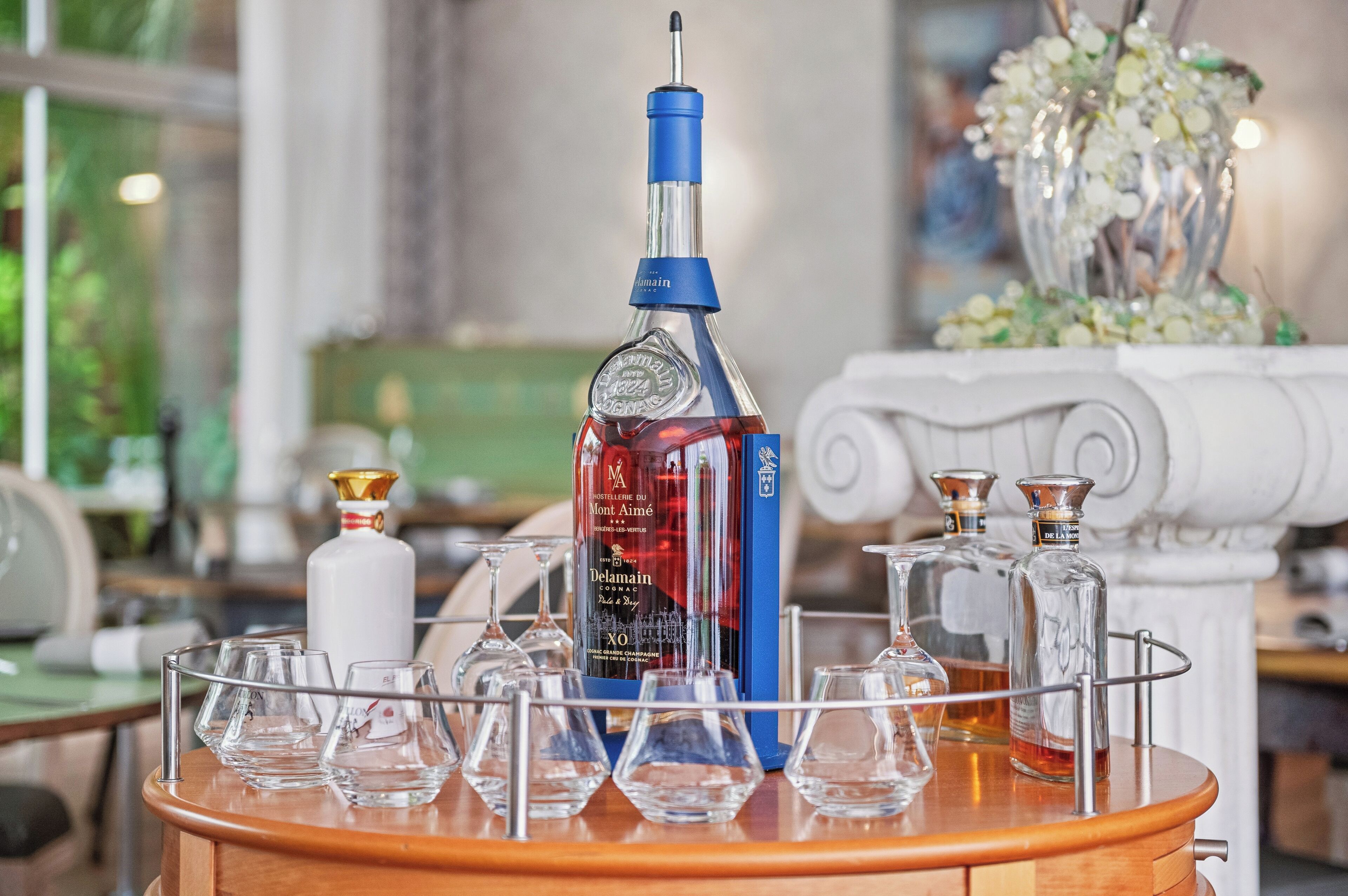 A bar area with a selection of liquor bottles and glasses on a wooden bar counter.
