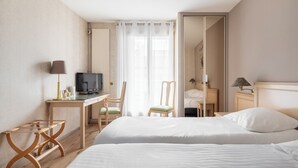 Ein Hotelzimmer mit zwei Betten, einem Schreibtisch, einem Fernseher, einem Stuhl und einem Spiegel.
