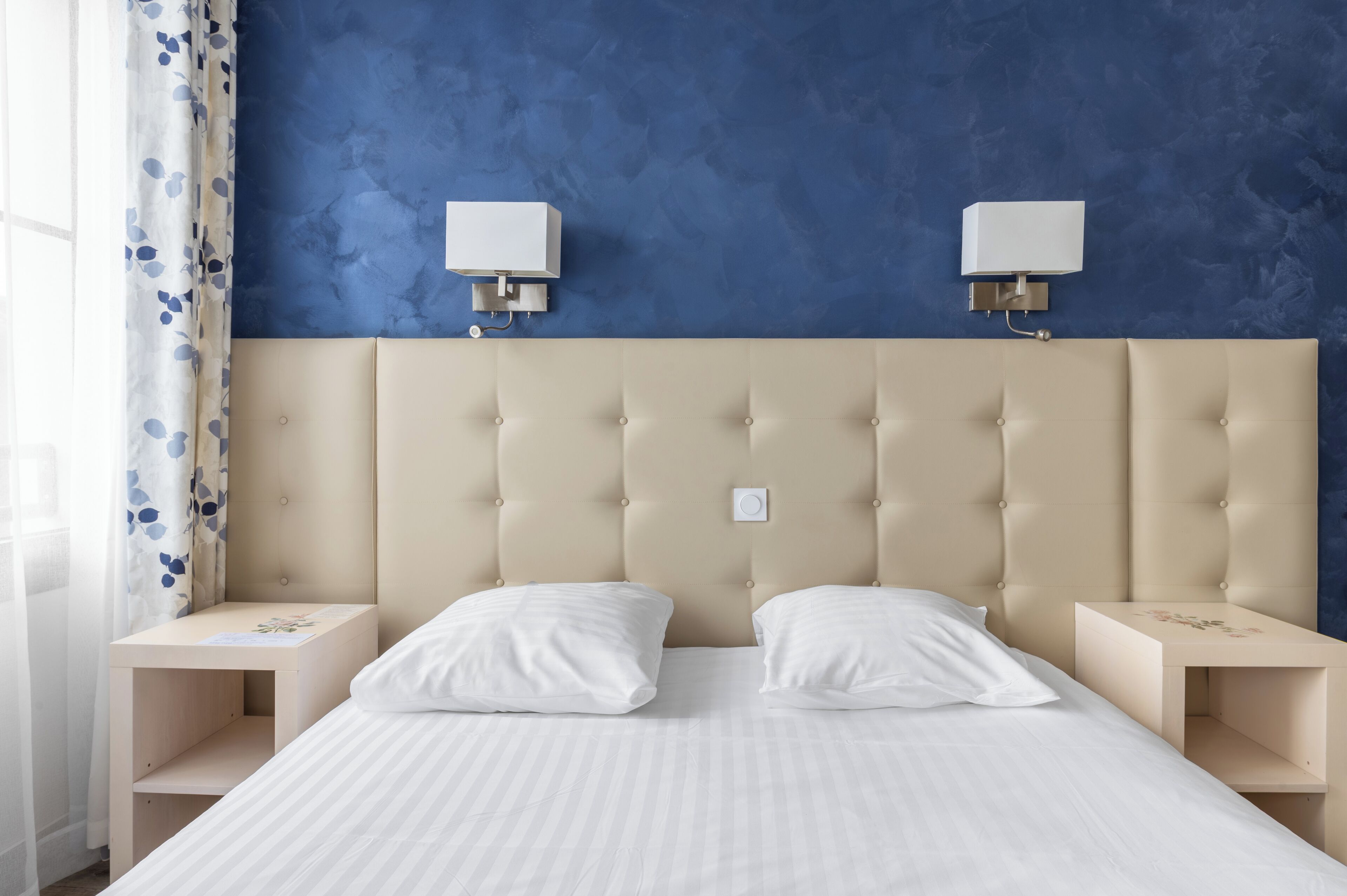 Ein Schlafzimmer mit einem gesteppten Kopfteil, zwei Nachttischen und einem Bett mit weißer Bettwäsche.