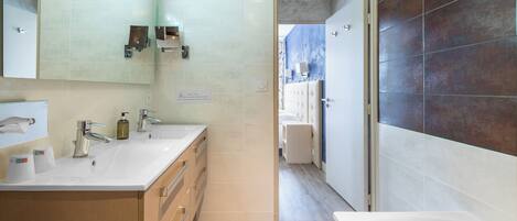 Un baño moderno con lavamanos doble, un espejo grande y una bañera.