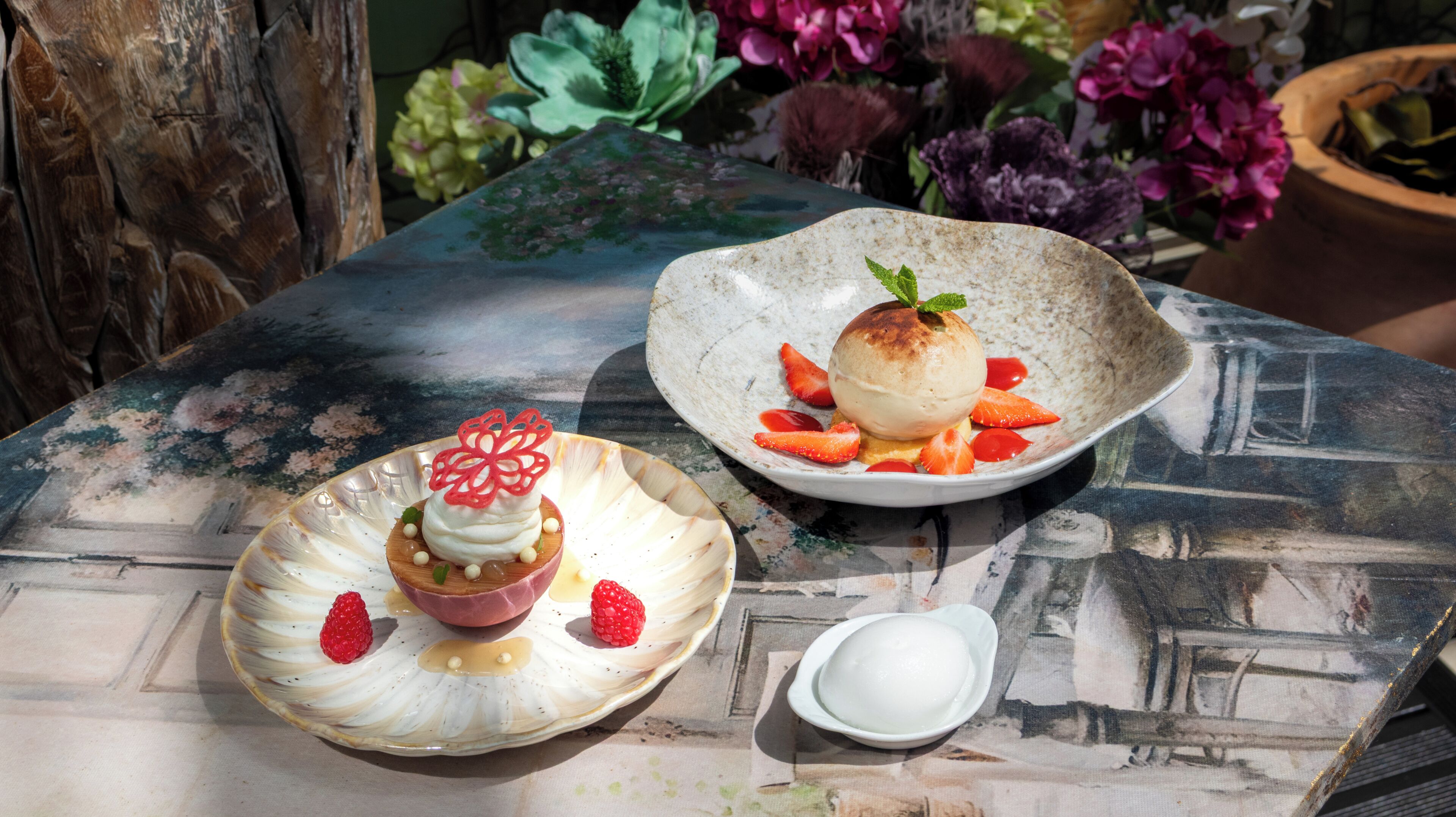 To desserttallerkener på et bord med blomstermønster og en lille skål fløde.