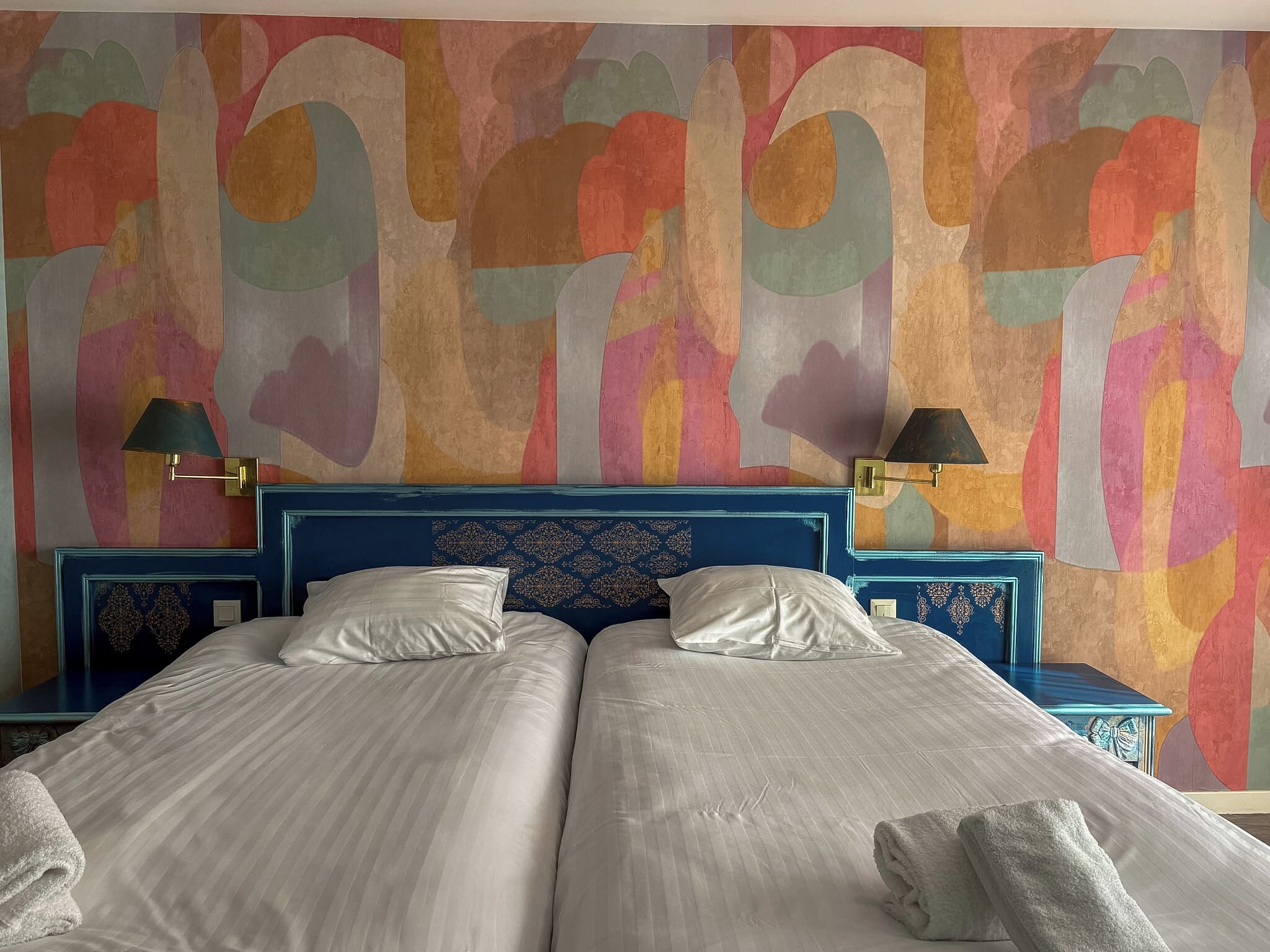 A double bed with two pillows, a headboard, and two bedside tables with lamps.
