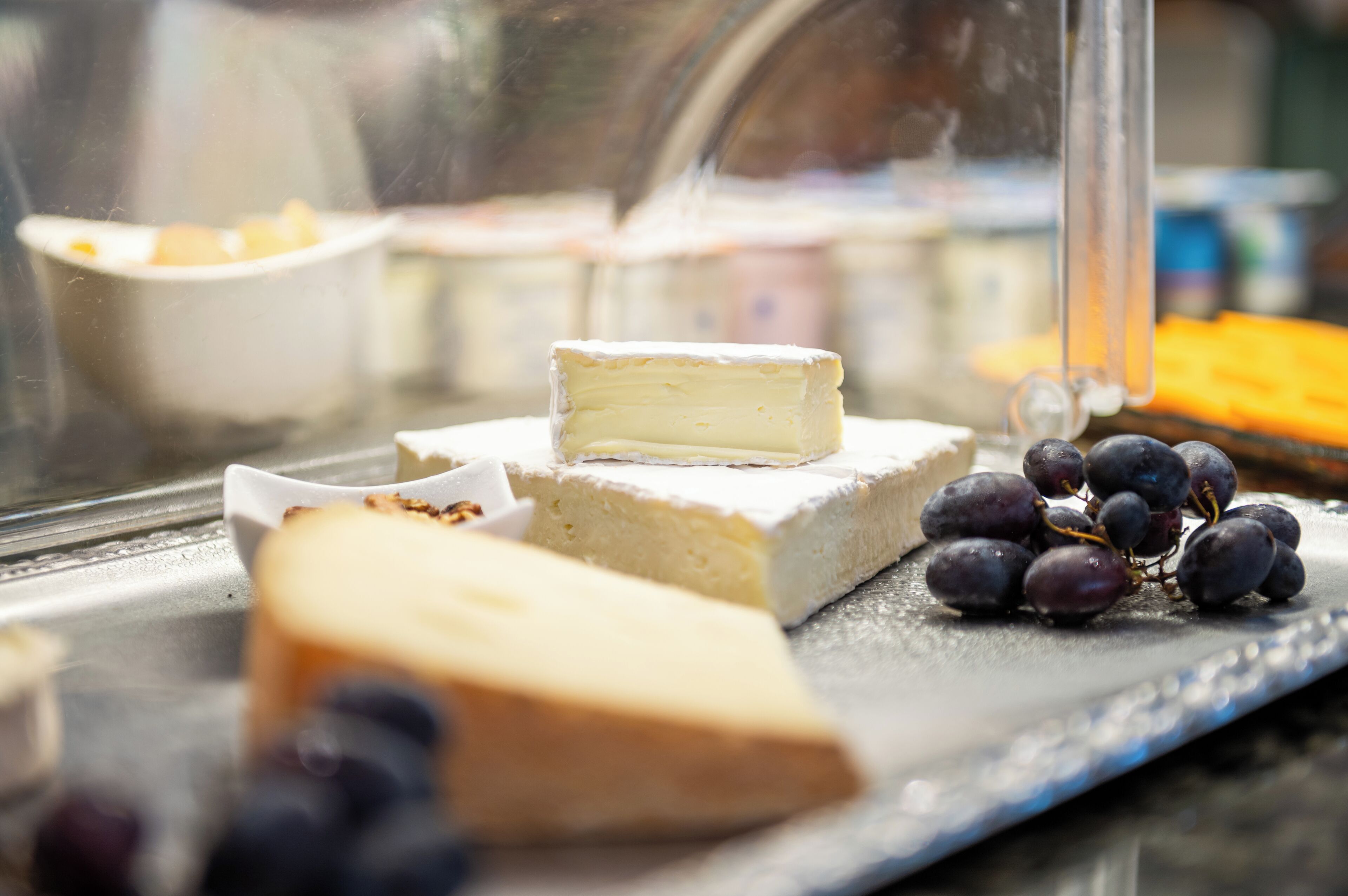 A cheese board with various cheeses and grapes.