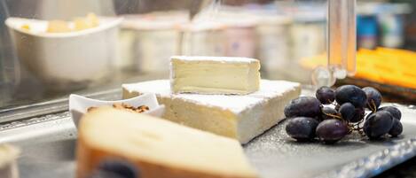 A cheese board with various cheeses and grapes.