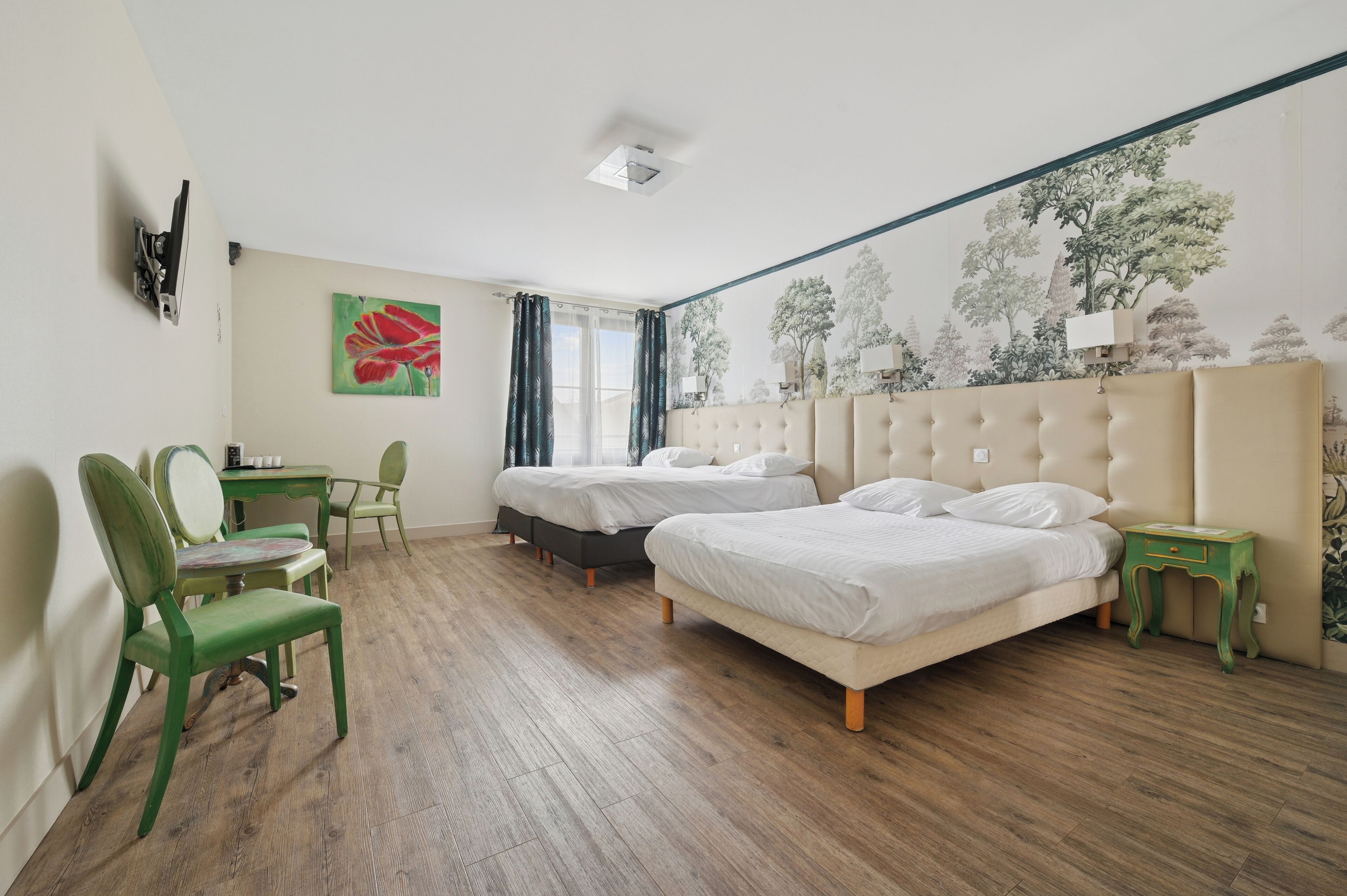 A bedroom with two beds, a desk, a chair, and a wall mural.