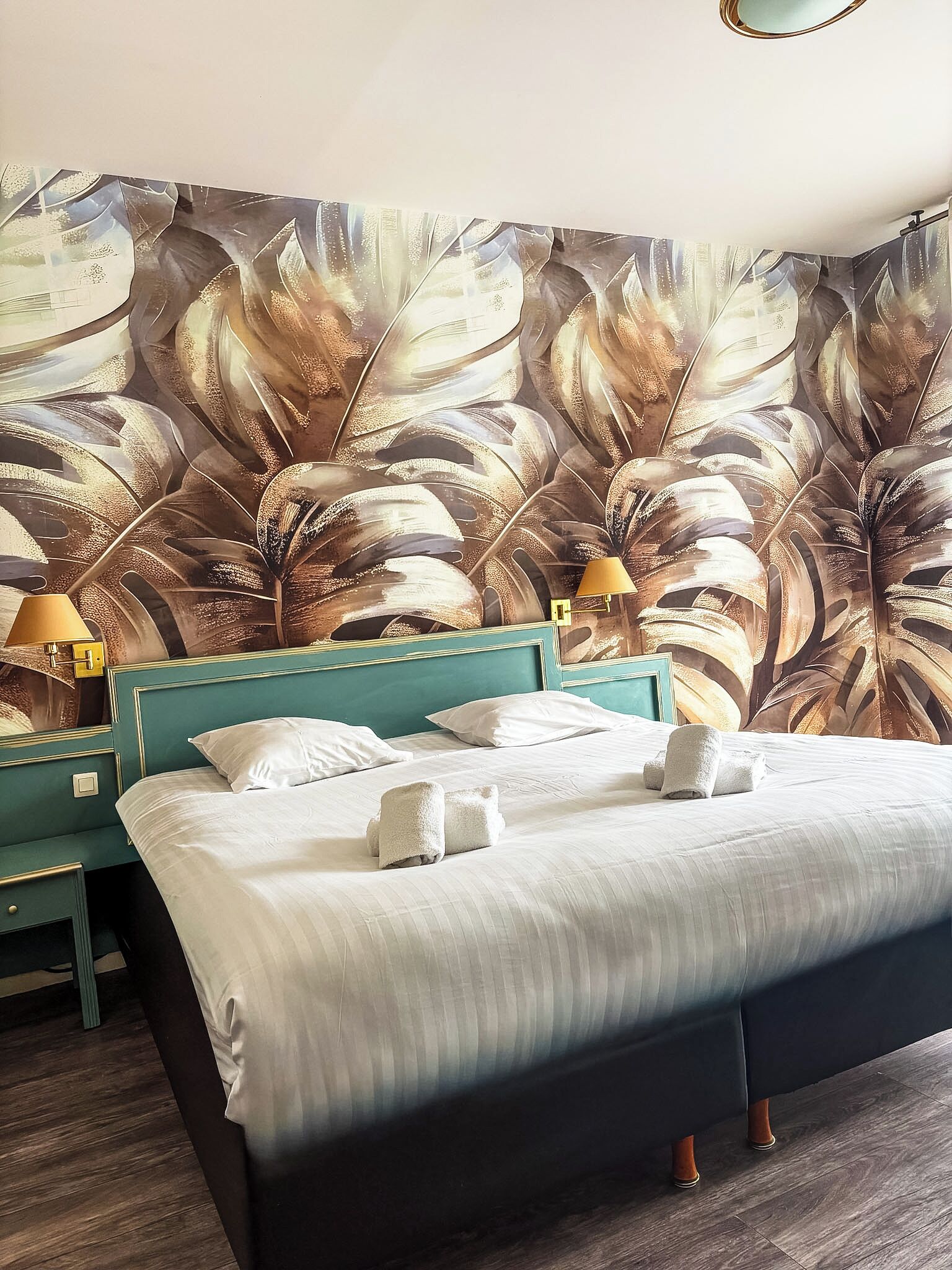 Una habitación de hotel con una cama grande, dos mesitas de noche y un mural en la pared.