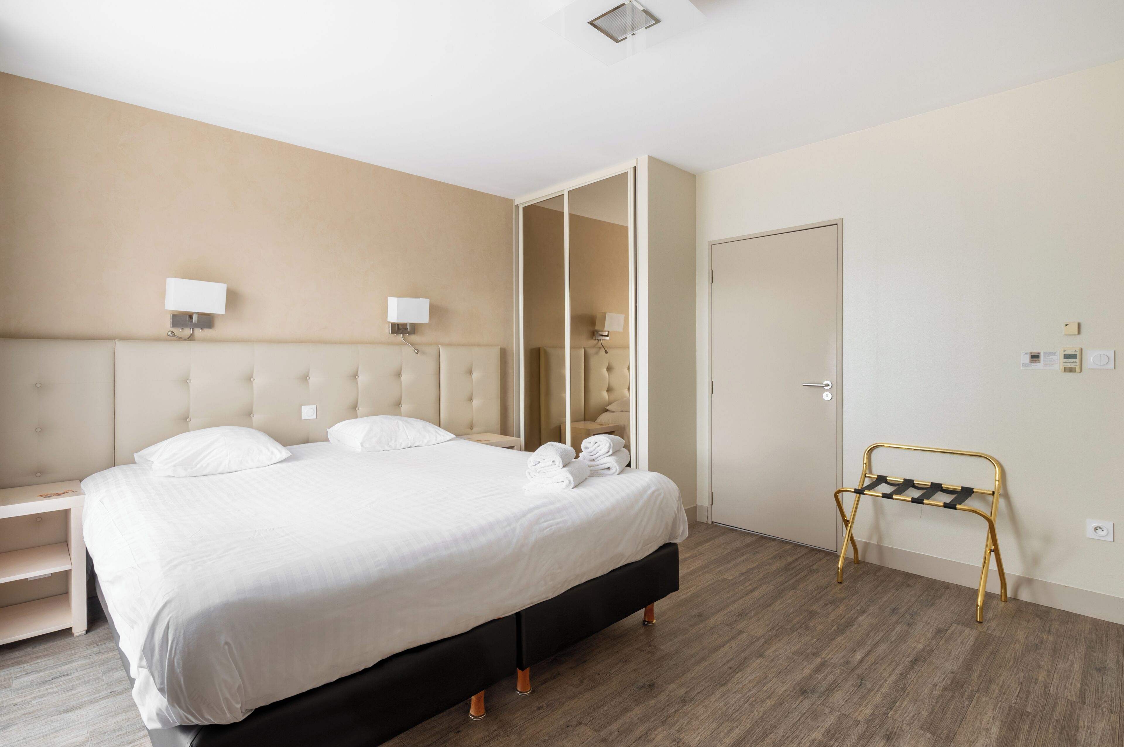 Camera d'albergo con un letto grande, lampade sui comodini, un armadio e un piccolo tavolo con asciugamani.