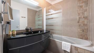 A modern bathroom with a curved vanity, a glass shower enclosure, and a bathtub.