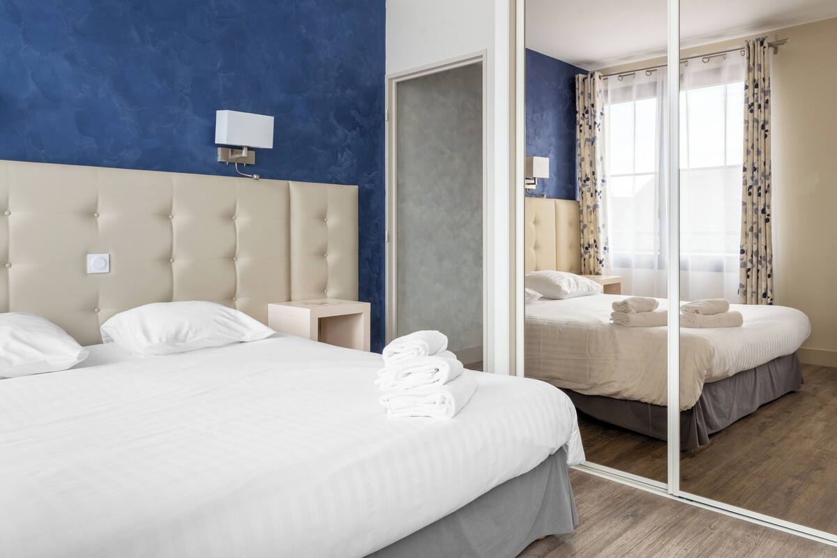 Een moderne hotelkamer met een groot bed, een nachtkastje, een wandlamp en een grote spiegel.