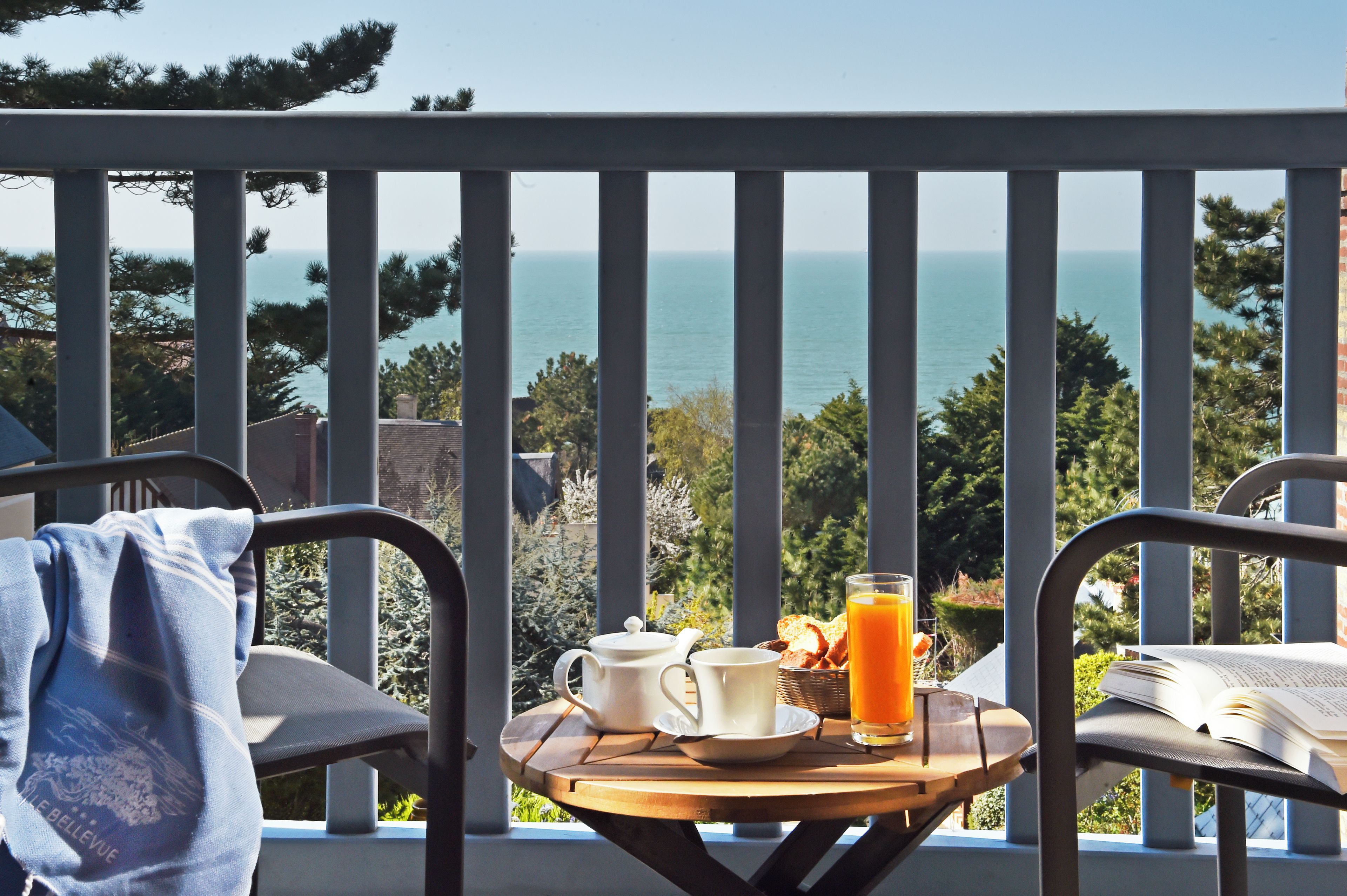 Een balkon met een ontbijttafel, met uitzicht op de kust.