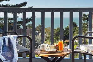 Un balcón con una mesa dispuesta para el desayuno, con vistas a la costa.