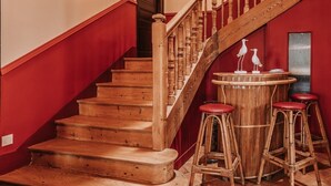 A wooden staircase with red walls and a round bar area with stools. - Hotel Restaurant Le Bellevue (Villerville)