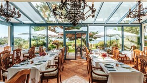 A restaurant with tables set for dining, a glass ceiling, and outdoor views. - Hotel Restaurant Le Bellevue (Villerville)