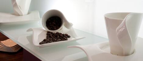Una cocina moderna con encimeras blancas, una cafetera y un recipiente con granos de café.