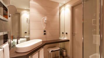 A modern bathroom with a large mirror, a glass shower enclosure, and a white sink.