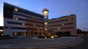 Un hotel moderno con una torre central, varios pisos y un área de entrada bien iluminada.