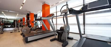 A modern gym with treadmills, elliptical machines, and weightlifting equipment.