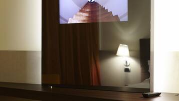 Un televisor montado en la pared, con un panel de madera y un control remoto sobre una superficie de madera.