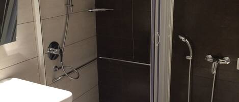 A modern bathroom with a shower enclosure, a sink, and a toilet.