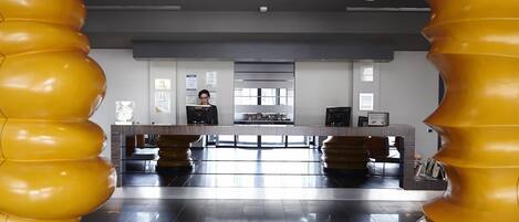 A modern reception area with a central desk, a large window, and a view of the lobby.