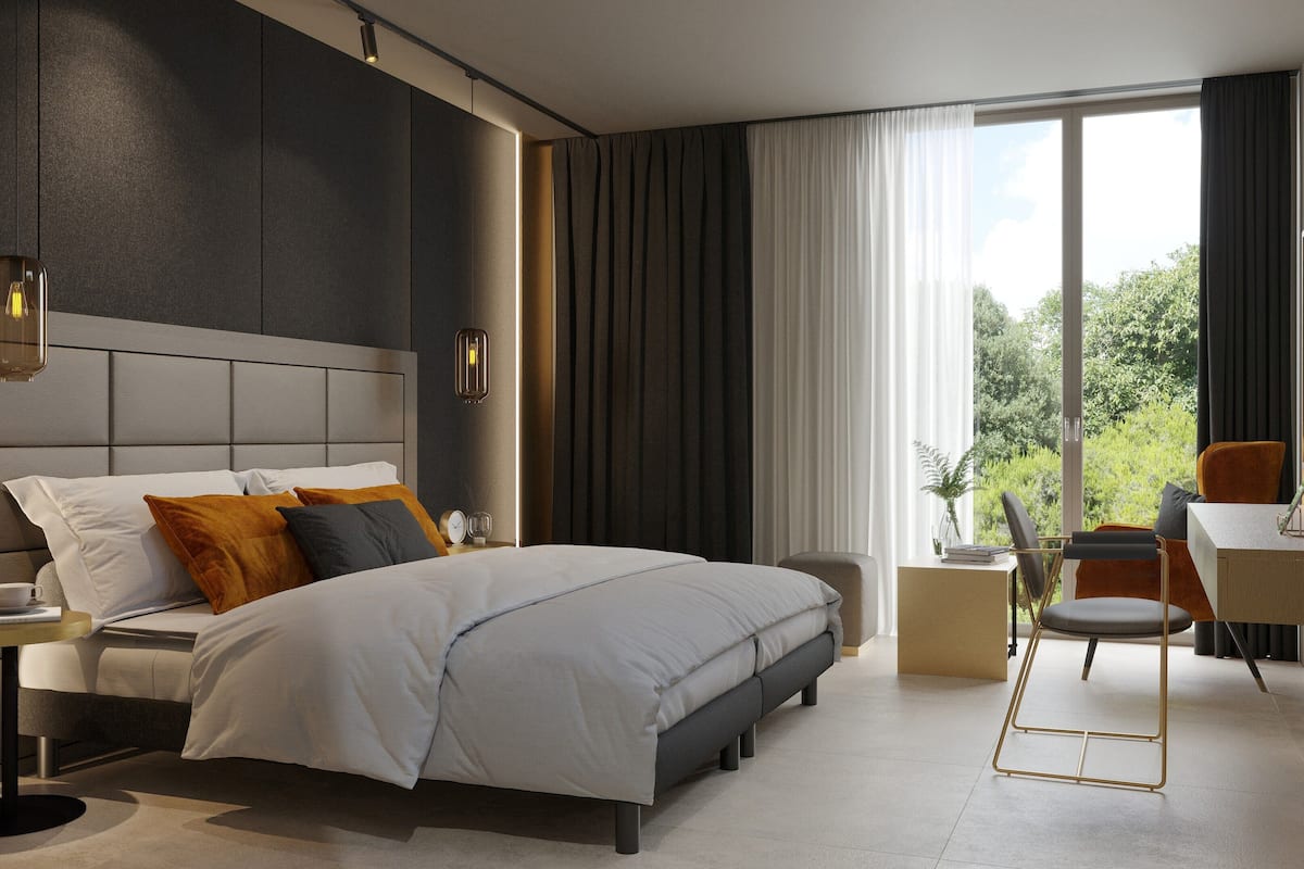 Un dormitorio moderno con una cama grande, mesitas de noche, un escritorio y vistas a zonas verdes por la ventana.