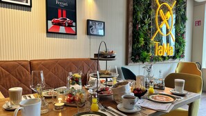Comedor con una mesa dispuesta para dos, que incluye una jarra de fruta, una taza de café y un menú.
